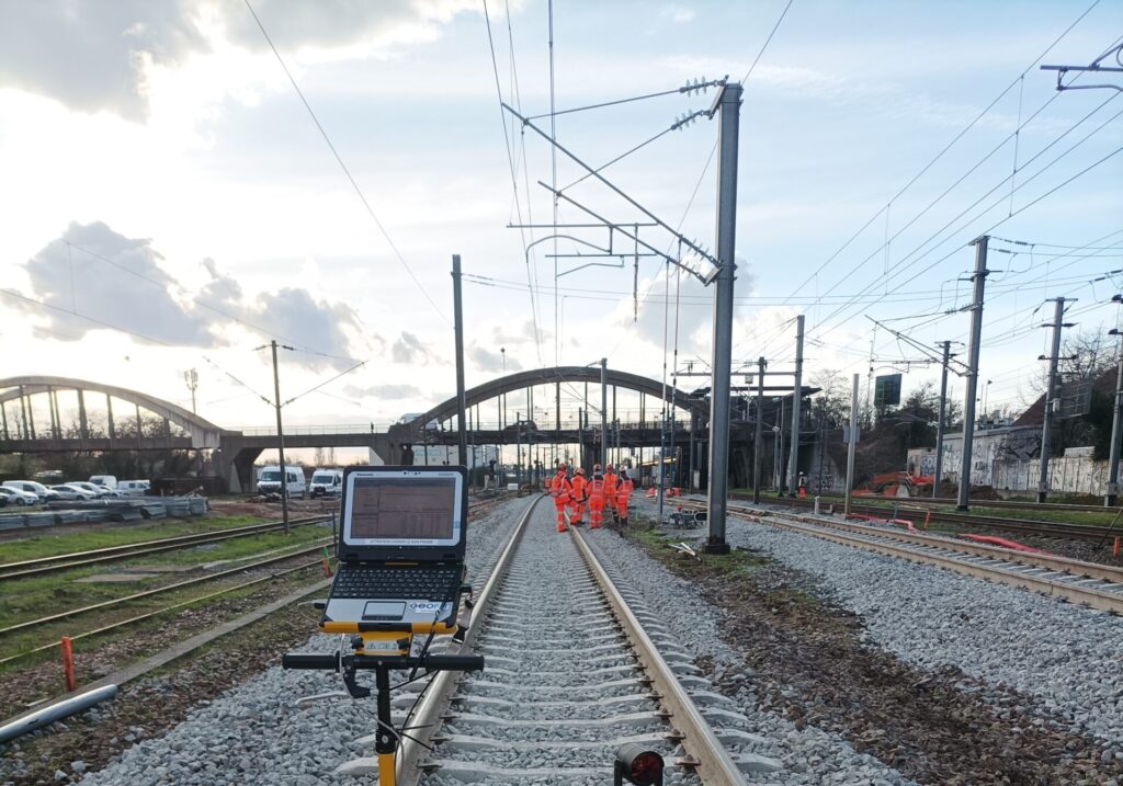 Equipe de géomètres prenant des mesures sur les voies du train pour le chantier du CDG Express.